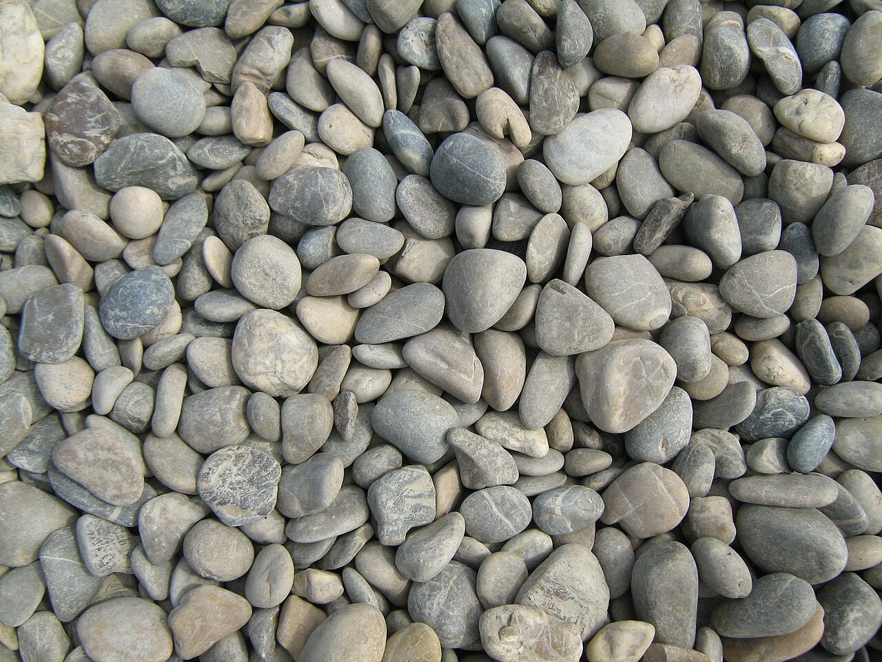 Closely packed gray and beige Danube pebbles with rounded edges and varied flattened shapes.